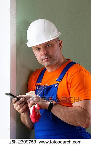 Stock Photo - Construction worker in hardhat using smart phone. Fotosearch