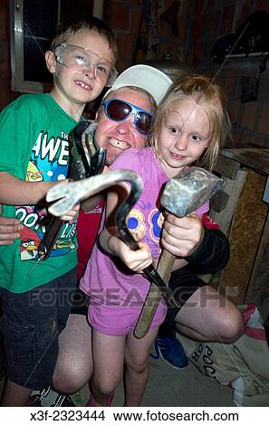 Dad and children in garage holding tools helping to repair furnace. Zawady Central Poland. View Large Photo Image Picture - Dad and children in garage holding tools helping to repair furnace. Zawady Central Poland.. Fotosearch