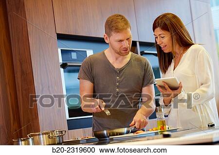 Family in the kitchen. Couple cooking and looking recipe on a tablet. Healthy eating. Healthy growth. View Large Photo Image Stock Image - Family in the kitchen. Couple cooking and looking recipe on a tablet. Healthy eating. Healthy growth.. Fotosearch