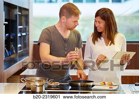Family in the kitchen. Couple cooking and looking recipe on a tablet. Healthy eating. Healthy growth. View Large Photo Image Stock Image - Family in the kitchen. Couple cooking and looking recipe on a tablet. Healthy eating. Healthy growth.. Fotosearch
