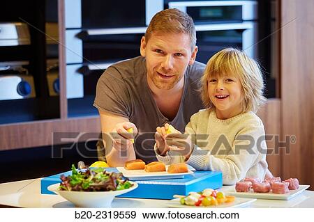 Family in the kitchen. Father and son. Healthy eating. Healthy growth. Taking lemon fish. View Large Photo Image Stock Photo - Family in the kitchen. Father and son. Healthy eating. Healthy growth. Taking lemon fish.. Fotosearch