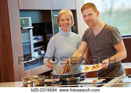 Picture - Family in the kitchen. Mother and son. Healthy eating. Healthy growth. Cooking fish and vegetable skewer.. Fotosearch