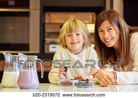 Stock Image - Family in the kitchen. Mother and son. Healthy eating. Healthy growth. Making milkshakes with berries.. Fotosearch