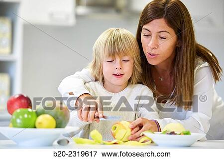 Stock Photo - Family in the kitchen. Mother and son. Healthy eating. Healthy growth. Peeling an apple.. Fotosearch