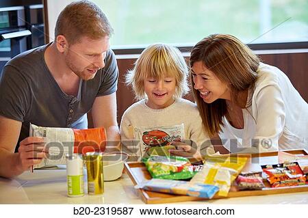 Stock Photo - Family in the kitchen. Parents and son. Healthy eating. Healthy growth. Packaged foods.. Fotosearch