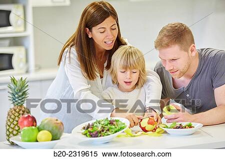 Stock Photography - Family in the kitchen. Parents and son. Healthy eating. Healthy growth. Peeling an apple.. Fotosearch