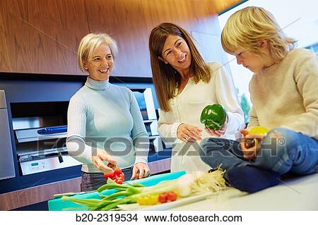 Picture - Family in the kitchen. Three generations. Healthy eating. Healthy growth. Vegetables.. Fotosearch