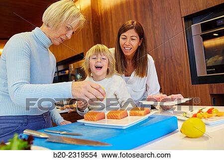 Family in the kitchen. Three generations. Healthy eating. Healthy growth. Taking lemon fish. View Large Photo Image Picture - Family in the kitchen. Three generations. Healthy eating. Healthy growth. Taking lemon fish.. Fotosearch