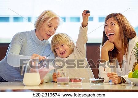 Picture - Family in the kitchen. Three generations. Healthy eating. Healthy growth. Making milkshakes with berries.. Fotosearch
