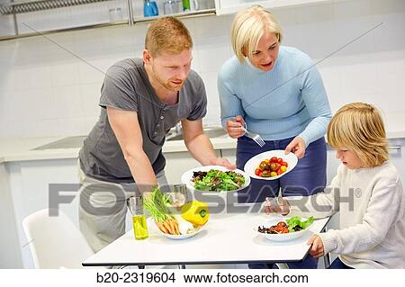 Picture - Family in the kitchen. Three generations. Healthy eating. Healthy growth. Making vegetable salad.. Fotosearch