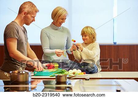 Stock Image - Family in the kitchen. Three generations. Healthy eating. Healthy growth. Vegetables.. Fotosearch