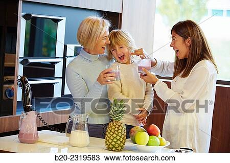 Stock Image - Family in the kitchen. Three generations. Healthy eating. Healthy growth. Making milkshakes with berries.. Fotosearch