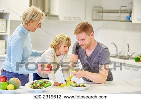 Stock Image - Family in the kitchen. Three generations. Healthy eating. Healthy growth. Peeling an apple.. Fotosearch