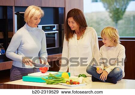 Stock Photo - Family in the kitchen. Three generations. Healthy eating. Healthy growth. Vegetables.. Fotosearch