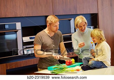 Stock Photo - Family in the kitchen. Three generations. Healthy eating. Healthy growth. Vegetables.. Fotosearch
