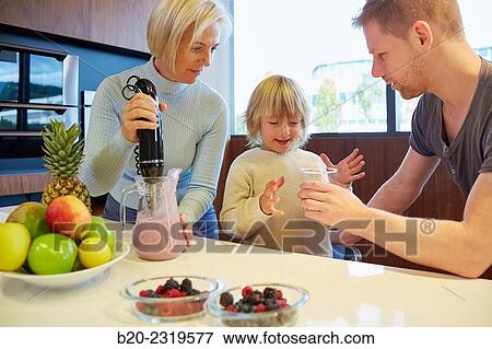 Stock Photo - Family in the kitchen. Three generations. Healthy eating. Healthy growth. Making milkshakes with berries.. Fotosearch