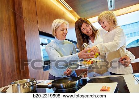 Stock Photo - Family in the kitchen. Three generations. Healthy eating. Healthy growth. Cooking fish and vegetable skewer.. Fotosearch