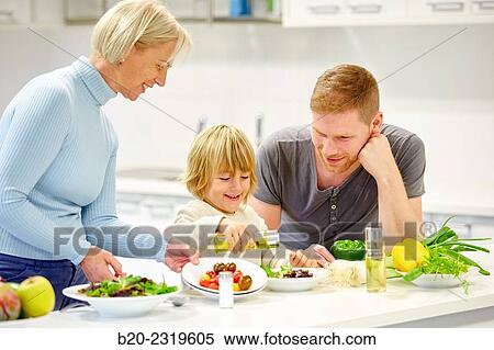 Stock Photography - Family in the kitchen. Three generations. Healthy eating. Healthy growth. Making vegetable salad.. Fotosearch