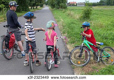 Father and three children preparing to bicycle down country road. Zawady Central Poland. View Large Photo Image Stock Photo - Father and three children preparing to bicycle down country road. Zawady Central Poland.. Fotosearch
