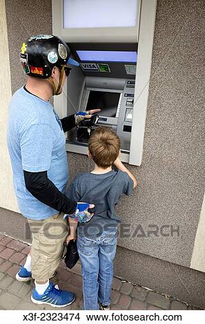 Father wearing a bicycle helmet and son age 38 and 8 working an outdoor ATM Bankomat cash machine. Rzeczyca Central Poland. View Large Photo Image Picture - Father wearing a bicycle helmet and son age 38 and 8 working an outdoor ATM Bankomat cash machine. Rzeczyca Central Poland.. Fotosearch