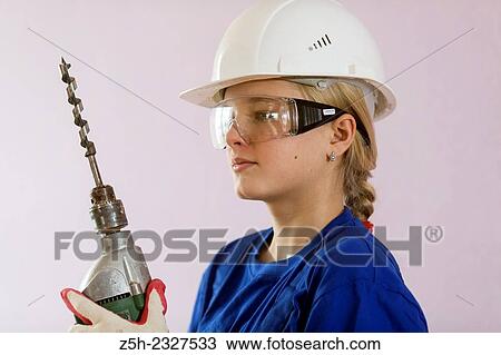 Stock Image - Girl in working clothes with construction tools.. Fotosearch