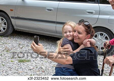 Inspired mom taking a selfie of her and daughter right in the middle of a parking lot age 6 and 34. Spala Central Poland. View Large Photo Image Stock Image - Inspired mom taking a selfie of her and daughter right in the middle of a parking lot age 6 and 34. Spala Central Poland.. Fotosearch