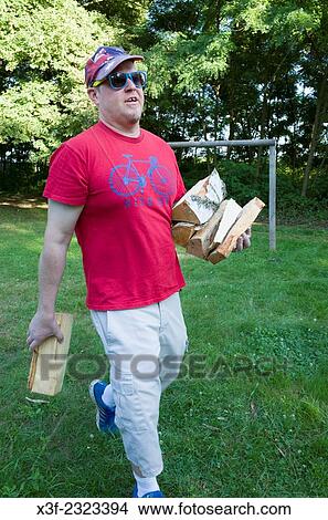 Man carrying split firewood to his outdoor barbecue fireplace. Zawady Central Poland. View Large Photo Image Picture - Man carrying split firewood to his outdoor barbecue fireplace. Zawady Central Poland.. Fotosearch