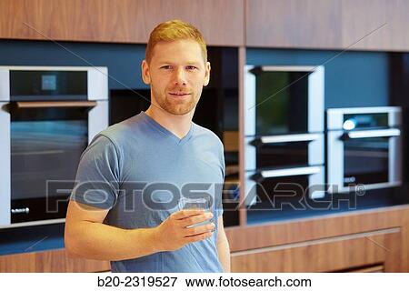 Stock Photo - Man drinking water in the kitchen.. Fotosearch