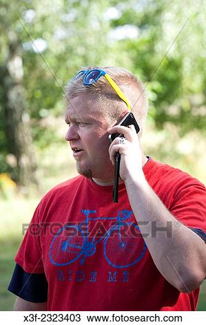 Man wearing a bicycle shirt talking on his cell phone. Zawady Central Poland. View Large Photo Image Stock Image - Man wearing a bicycle shirt talking on his cell phone. Zawady Central Poland.. Fotosearch