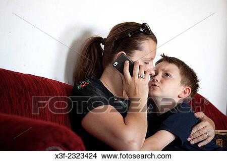 Mom trying to talk on phone while tending to young son. Lodz Central Poland. View Large Photo Image Picture - Mom trying to talk on phone while tending to young son. Lodz Central Poland.. Fotosearch