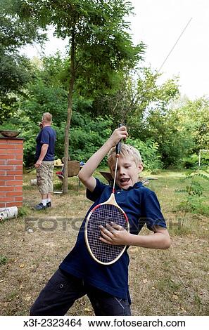 Polish boy age 10 playing air badminton guitar while father works at grill. Zawady Central Poland. View Large Photo Image Picture - Polish boy age 10 playing air badminton guitar while father works at grill. Zawady Central Poland.. Fotosearch