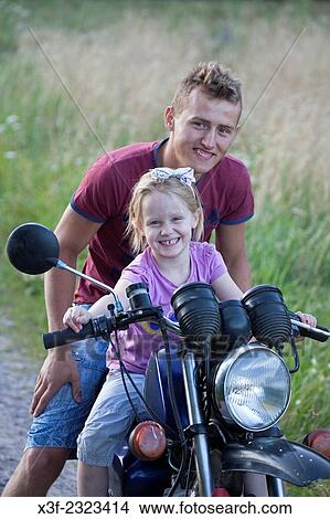 Polish teen boy motorcyclist giving ride to excited neighbor girl age 18 and 5. Zawady Central Poland. View Large Photo Image Picture - Polish teen boy motorcyclist giving ride to excited neighbor girl age 18 and 5. Zawady Central Poland.. Fotosearch