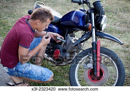 Polish teenage 18 blowing on spark plug while repairing his motorcycle. Zawady Central Poland. View Large Photo Image Stock Image - Polish teenage 18 blowing on spark plug while repairing his motorcycle. Zawady Central Poland.. Fotosearch
