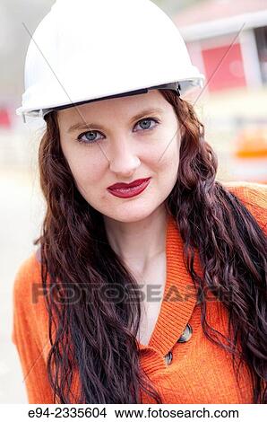 Picture - Portrait of a 33 year old brunette woman wearing a hard hat looking directly at the camera.. Fotosearch