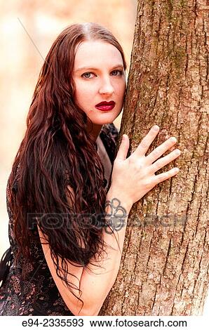 Portrait of a 33 year old brunette woman leaning on a tree and looking at the camera, outdoors. View Large Photo Image Stock Image - Portrait of a 33 year old brunette woman leaning on a tree and looking at the camera, outdoors.. Fotosearch
