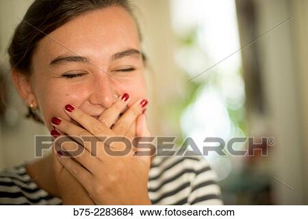 Picture - Portrait of young woman covering her mouth with hand, smiling, happy and joy. Fotosearch
