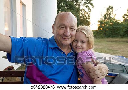 Proud Polish grandfather embracing his granddaughter on porch of summer home age 60 and 6. Zawady Central Poland. View Large Photo Image Stock Photograph - Proud Polish grandfather embracing his granddaughter on porch of summer home age 60 and 6. Zawady Central Poland.. Fotosearch
