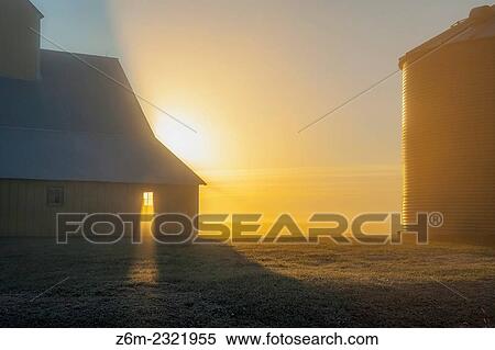 Stock Photography - Sun rays shine through barn window on foggy morning in western Iowa.. Fotosearch
