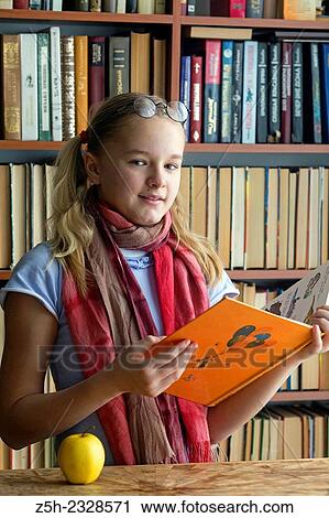 Stock Image - The girl with green apple and a book.. Fotosearch