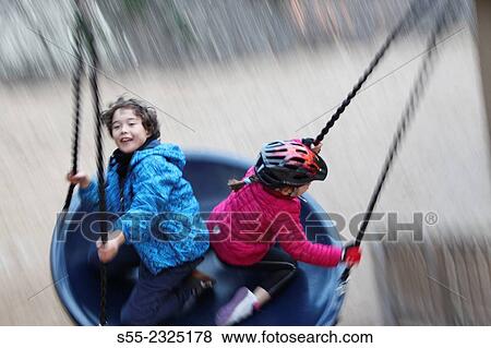 Two kids of 7 and 9 year old swinging. Barcelona, Catalonia, Spain View Large Photo Image Stock Photo - Two kids of 7 and 9 year old swinging. Barcelona, Catalonia, Spain. Fotosearch