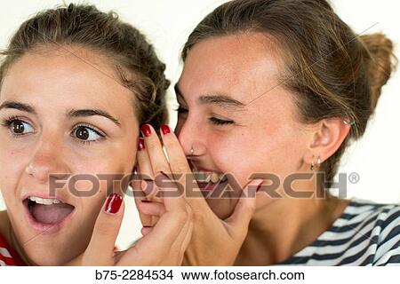 Two young girls whispering and sharing a secret with surprise View Large Photo Image Picture - Two young girls whispering and sharing a secret with surprise. Fotosearch