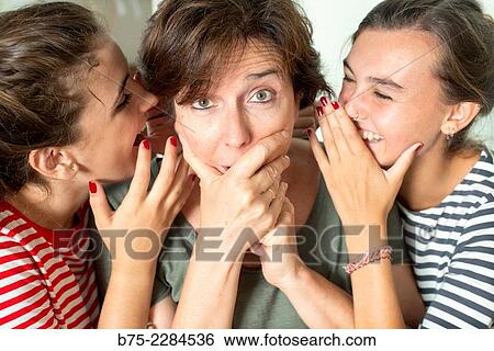 Two young girls with her mother whispering and sharing a secret with surprise View Large Photo Image Stock Photograph - Two young girls with her mother whispering and sharing a secret with surprise. Fotosearch