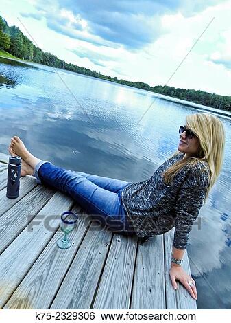 Woman sitting on dock at lake relaxing View Large Photo Image Stock Photograph - Woman sitting on dock at lake relaxing. Fotosearch