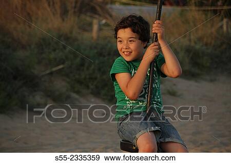 Young boy swinging. El Prat de Llobregat beach. Barcelona province, Catalonia, Spain. View Large Photo Image Stock Photo - Young boy swinging. El Prat de Llobregat beach. Barcelona province, Catalonia, Spain.. Fotosearch
