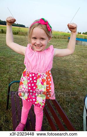 Young girl age 6 showing her muscles on family outing. Zawady Central Poland. View Large Photo Image Stock Photo - Young girl age 6 showing her muscles on family outing. Zawady Central Poland.. Fotosearch