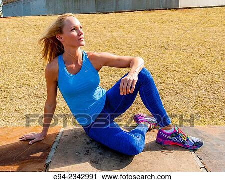 39 year old blond woman wearing fitness clothing sitting on a stone wall in the afternoon sun. View Large Photo Image Stock Image - 39 year old blond woman wearing fitness clothing sitting on a stone wall in the afternoon sun.. Fotosearch