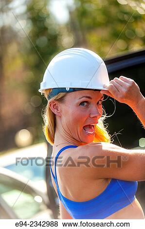 Stock Photo - 39 year old blond woman wearing fitness clothing and a white hard hat making a face at the camera. Fotosearch
