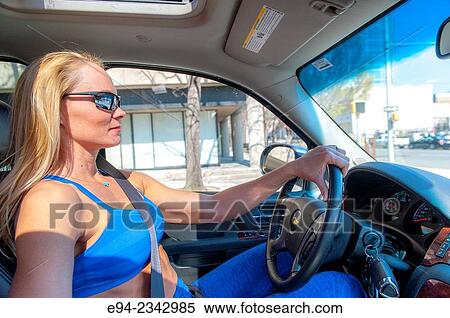 Stock Photography - 39 year old blond woman wearing fitness clothing driving a car and wearing sunglasses.. Fotosearch