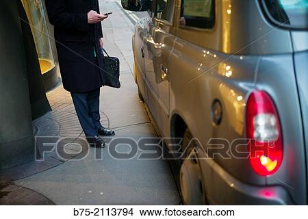 A unrecognizable man with a phone in one hand and a briefcase in the other, by a taxi. London, England, UK, Europe. View Large Photo Image Picture - A unrecognizable man with a phone in one hand and a briefcase in the other, by a taxi. London, England, UK, Europe.. Fotosearch