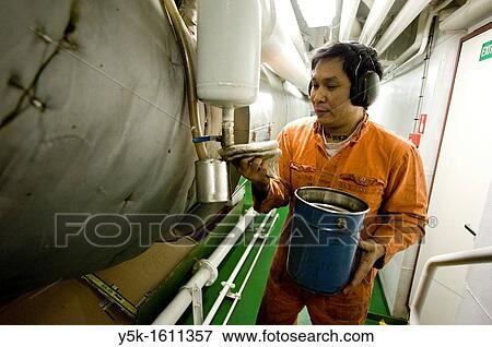 An Indonesian seaman or sailor on the container-vessel MV Flintercape, during a journey from Rotterdam, Netherlands, to Sundsvall, Sweden. The man is an 'Able Seaman', who generally works in the engine-room. He is now checking oil-levels. View Large Photo Image Stock Photo - An Indonesian seaman or sailor on the container-vessel MV Flintercape, during a journey from Rotterdam, Netherlands, to Sundsvall, Sweden. The man is an 'Able Seaman', who generally works in the engine-room. He is now checking oil-levels.. Fotosearch